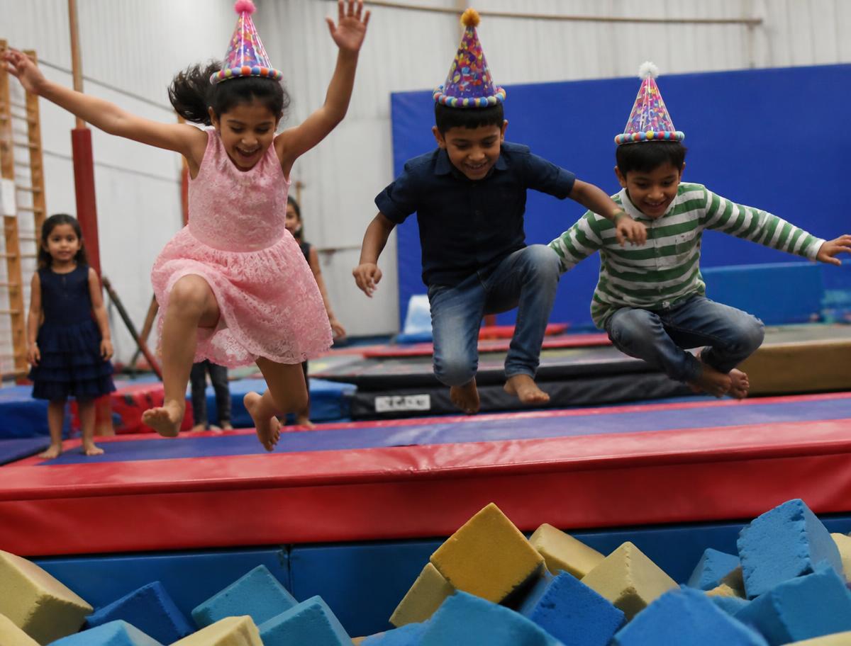 Kids in party hats jumping into the foam pit at a Tumble Gym birthday party