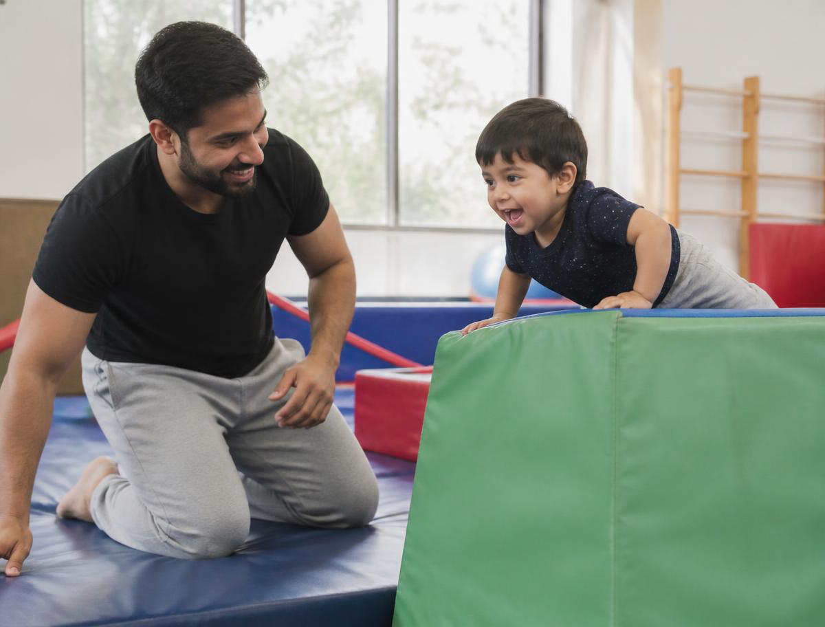 Father and toddler playing on soft gym equipment at Tumble Gym